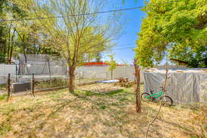 Fenced backyard featuring a trampoline