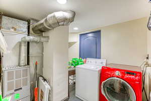 Laundry area featuring independent washer and dryer, recessed lighting, and heating unit