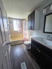 Full bathroom with shower / bath combination with curtain, vanity, a textured ceiling, and dark wood-style floors