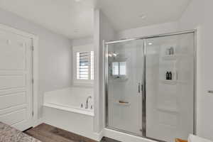 Full bathroom with a stall shower, a bath, and dark wood finished floors