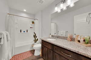 Full bathroom with shower / bath combo with shower curtain, vanity, dark wood-style flooring, and recessed lighting
