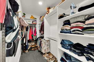 Spacious closet featuring dark colored carpet