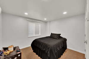 Bedroom with light colored carpet and recessed lighting