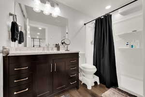 Full bathroom featuring dark wood-style floors, vanity, recessed lighting, and a shower stall