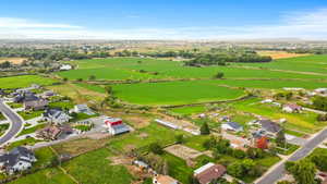 Aerial view of property and surrounding area featuring rural landscape, mountains, and nearby suburban area