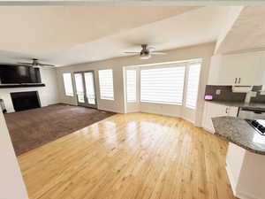 Unfurnished living room with a fireplace, plenty of natural light, a ceiling fan, and light wood-style flooring