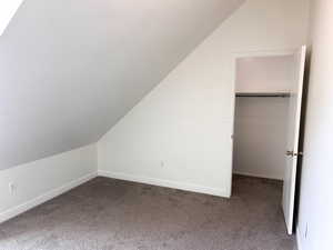 Upstairs west room featuring carpet flooring and lofted ceiling and walk in closet
