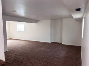 Empty room with dark carpet and a textured ceiling