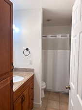 Upstairs full bath with vanity, curtained shower, and light tile patterned flooring