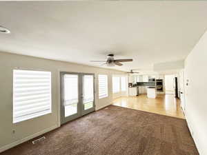 Unfurnished living room featuring light carpet and french doors