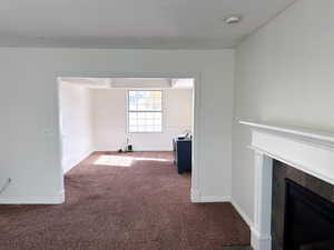 Unfurnished living room with dark colored carpet and a tiled fireplace