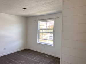 Upstairs north room with dark colored carpet and a textured ceiling