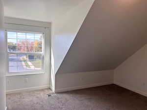 Upstairs west room featuring carpet flooring and lofted ceiling and walk in closet