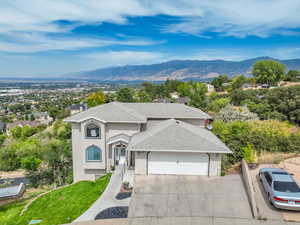 Traditional-style house featuring roof with shingles, stucco siding, a mountain view, driveway, and an attached garage