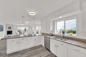 Kitchen featuring dark stone countertops, a peninsula, healthy amount of natural light, and hanging light fixtures