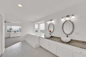 Full bathroom with healthy amount of natural light, a garden tub, double vanity, and recessed lighting