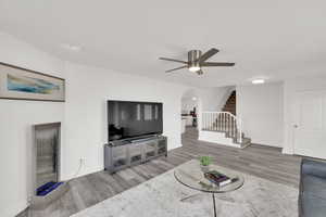 Living room with wood finished floors, arched walkways, stairway, and a ceiling fan