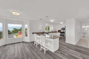 Kitchen with white cabinetry, light wood-type flooring, a breakfast bar, a peninsula, and appliances with stainless steel finishes