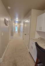 Hallway featuring a textured ceiling and light carpet