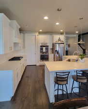 Kitchen featuring pendant lighting, white cabinets, stainless steel appliances, a breakfast bar, and recessed lighting