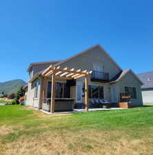 Back of house with a hot tub, stucco, a patio area, a pergola, and a yard
