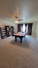 Family room with light carpet, large windows and a ceiling fan