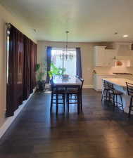 Dining space with a textured ceiling, a chandelier, and dark wood finished floors