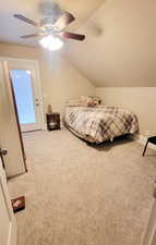 Upstairs bedroom featuring access to outside, ceiling fan, and vaulted ceiling and a walk-in closet