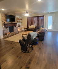 Living area with a textured ceiling, dark wood finished floors, a fireplace, recessed lighting, and a ceiling fan
