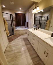 Master bathroom featuring double vanity, a stall shower, a garden tub, recessed lighting, and light tile patterned flooring
