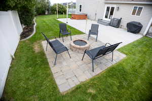 Fenced backyard with a hot tub, a patio area, area for grilling, and an outdoor fire pit