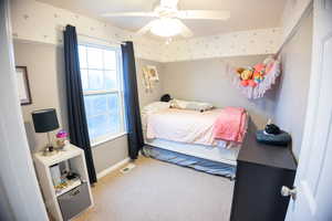 Bedroom with light colored carpet and a ceiling fan