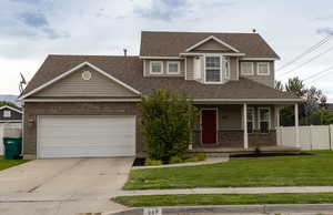 Traditional home featuring covered porch, driveway, brick siding, a garage, and a shingled roof