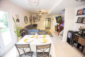 Dining space with stairs, light wood-type flooring, and a ceiling fan