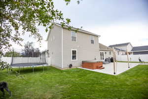 Rear view of property featuring a fenced backyard, a patio, a hot tub, and a trampoline