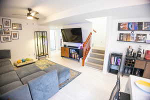 Living area featuring stairway, a ceiling fan, and wood finished floors