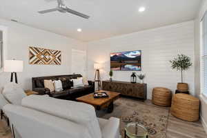 Living room featuring wood finished floors, recessed lighting, wood walls, and a ceiling fan