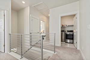 Hallway featuring light colored carpet, recessed lighting, washing machine and clothes dryer, an upstairs landing, and light tile patterned flooring