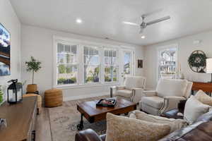 Living area with wood finished floors, ceiling fan, a textured ceiling, and recessed lighting