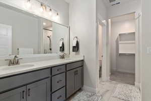 Full bath featuring a shower stall, double vanity, and light marble finish flooring