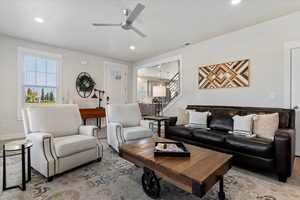 Living room with plenty of natural light, recessed lighting, ceiling fan, and stairway