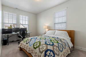 Carpeted bedroom featuring a desk and baseboards