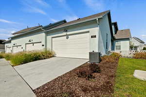 View of side of property featuring stucco siding, concrete driveway, and a shingled roof