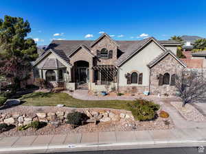 French country style house featuring stone siding, stucco siding, a porch, and a front lawn