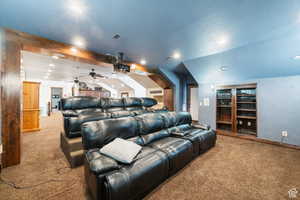 Carpeted home theater room featuring vaulted ceiling, recessed lighting, ceiling fan, and a textured ceiling