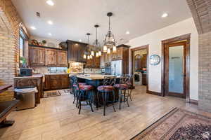 Kitchen with a kitchen breakfast bar, a kitchen island, brick wall, light stone countertops, and hanging light fixtures