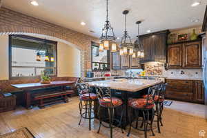 Kitchen with pendant lighting, light stone countertops, light wood-style flooring, an island with sink, and recessed lighting