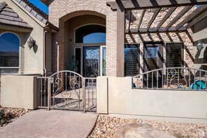 View of exterior entry featuring a gate, stucco siding, and brick siding