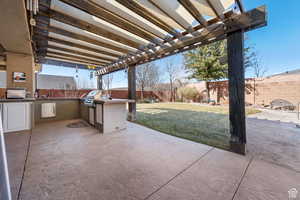 Fenced backyard with a pergola, a patio area, and an outdoor kitchen