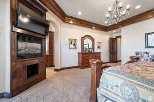 Bedroom featuring ornamental molding, light carpet, arched walkways, and a chandelier